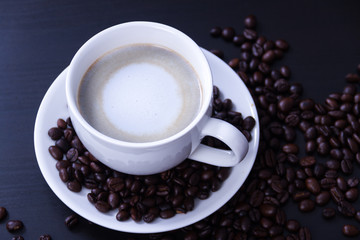 Hot coffee in the white cup and roasted on dark background