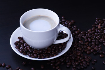 Hot coffee in the white cup and roasted on dark background