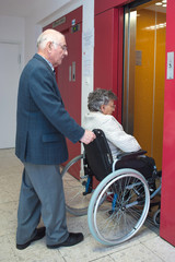 Fototapeta na wymiar pushing elderly lady in wheelchair in lift