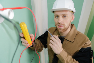 builder using a yellow multimeter to calibrate house
