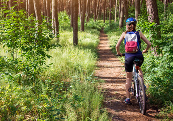Obraz premium Young woman riding a bicycle in the forest