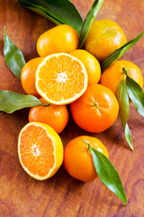 Fresh ripe mandarin oranges with green leaves on wooden table. Ready for making orange juice