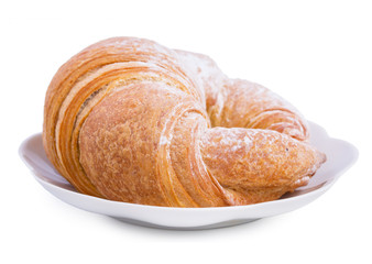 Fresh croissant on a saucer isolated on a white background, close up.