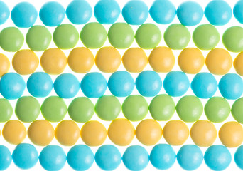 Round pastel candies in a pattern on a white background
