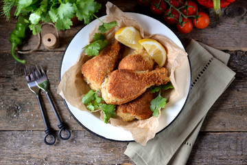 Chicken legs fried in breadcrumbs in deep-fried, rustic style. Old wooden background.