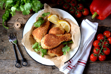 Chicken legs fried in breadcrumbs in deep-fried, rustic style. Old wooden background.