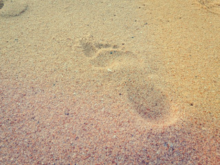 Fototapeta na wymiar Natural background of human footprint in the wet sandy seaside. Close-up photography on relaxation sign idea design