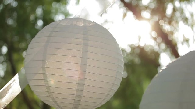 White lanterns blow gently in the breeze against the colored sky at sunrise or sunset  gently swaying in the wind. Valentine Day. Wedding day.