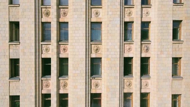 Aerial shot along the High-rise multi-storey vintage building with a large number of windows and stucco moldings. Summer day in the sunlight. Main building of Moscow State University, close-up