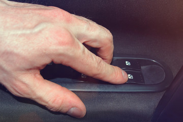 hand close-up pushes window lift button in the car