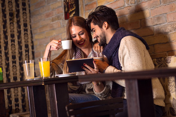 Beautiful young couple looking at tablet in cafe.