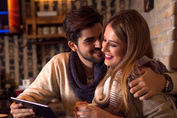 Beautiful young couple looking at tablet in cafe.