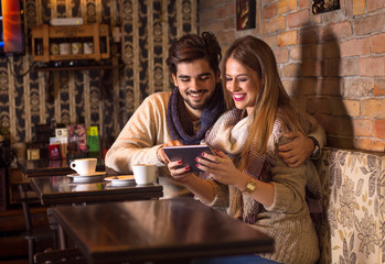 Beautiful young couple looking at tablet in cafe.