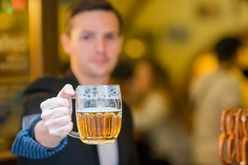 Young man with beer and salted soft pretzels in beer sport bar