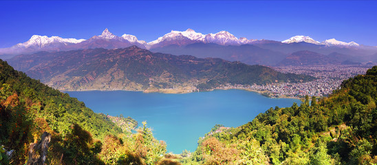 Naklejka na ściany i meble Himalayas. Horizontal panoramic view from hillside at the magnificent Annapurna mountain range, Phewa lake and Pokhara valley and a town.