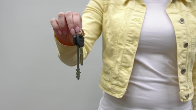 An unrecognizable woman holds out keys to the camera.