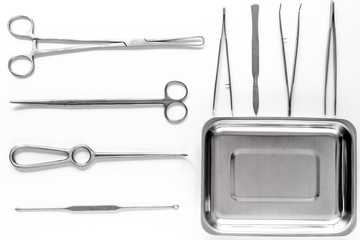 Surgical instruments and tools including scalpels, forceps and tweezers on white table top view mock up