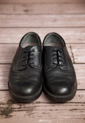 Fototapeta na wymiar Old Black Dress Shoes on a Wooden Floor