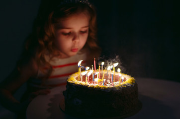 Birthday. A little sweet girl blows out candles on the stoke.