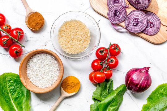 Cooking Paella With Vegetables And Rice Ingredients On White Desk Background Top View