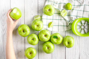 Fototapeta na wymiar natural food design with green apples in hands white desk background top view
