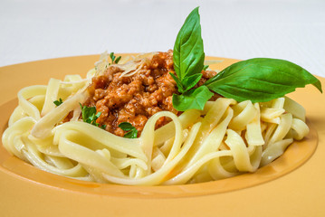 Tasty pasta with meat and herbs, on a yellow plate. Horizontal frame