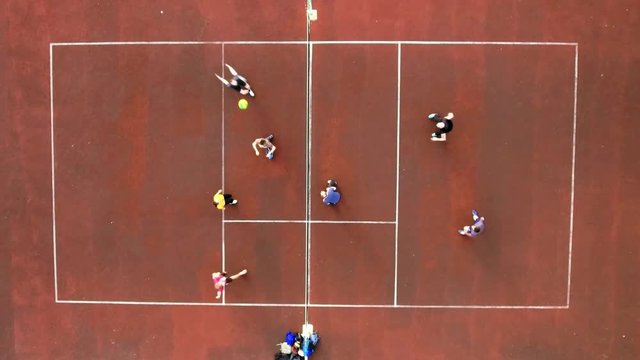 Top view of two teams playing volleyball on the court outdoors, jumping and beating the ball. Aerial shot. Match between teams on volleyball on the court with a red cover