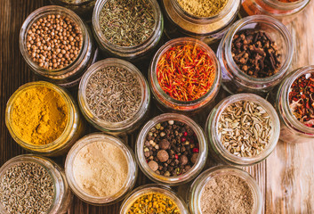Various colorful kinds of spices on rustic wooden table, top view