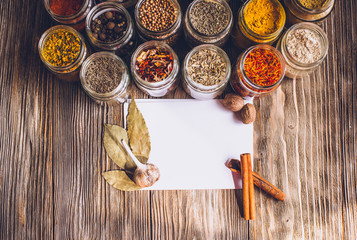 Various colorful kinds of spices on rustic wooden table, top view with copy space