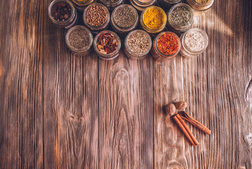 Obraz na płótnie Canvas Various colorful kinds of spices on rustic wooden table, top view with copy space