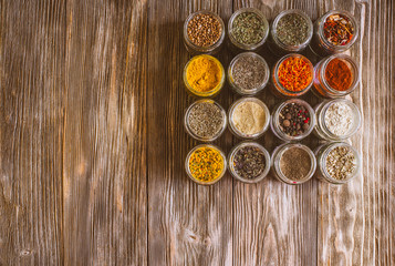 Fototapeta na wymiar Various colorful kinds of spices on rustic wooden table, top view with copy space