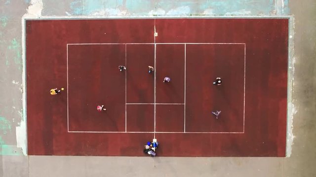 Aerial shot Match between two teams in volleyball outside. Two teams play volleyball through the grid in the open air, top view. Player gives the ball, the beginning of the game