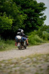 Man riding motorcycle with a woman on rural road. Young couple on motorbike through country road. Couple riding a motorcycle