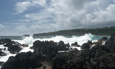 Pacific ocean breaks against lava rocks at Keanae