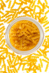 Backlit dried raw, uncooked spirelli pasta noodles in glass container