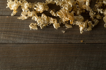 Light brown wood shavings from carpenter's hand planer or chisel work on wooden boards