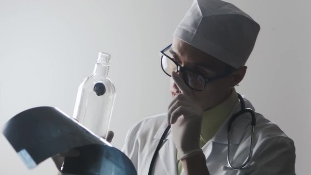 Drunk doctor makes a diagnosis. A medical worker drinks vodka.
