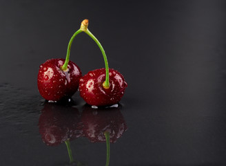 Cherry in droplets on a black background.