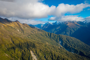 Beautiful landscape of the New Zealand - hills covered by green grass with mighty mountains covered by snow behind, South Island in New Zealand