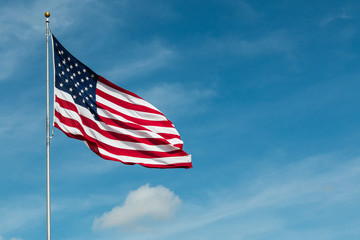 American Flag against the backdrop of a blue sky and clouds.   - Powered by Adobe