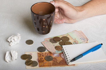Macedonian money in paper and metal, note pad and man's hand holding cup of coffee