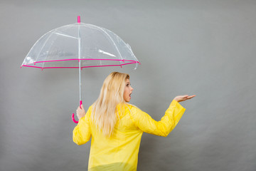 Woman wearing raincoat holding umbrella checking weather