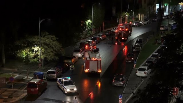Greek Fire Service tracks during fire at Thessaloniki, Greece. Hellenic Fire Brigade vehicles with Greek firefighters in uniform during a city fire at night.