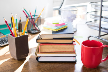 Stack of books and office supplies on wood table