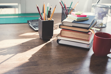 Stack of books and office supplies on wood table