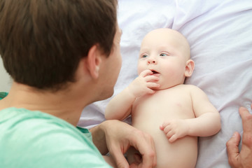 indoor portrait of young happy father with twin babies at home