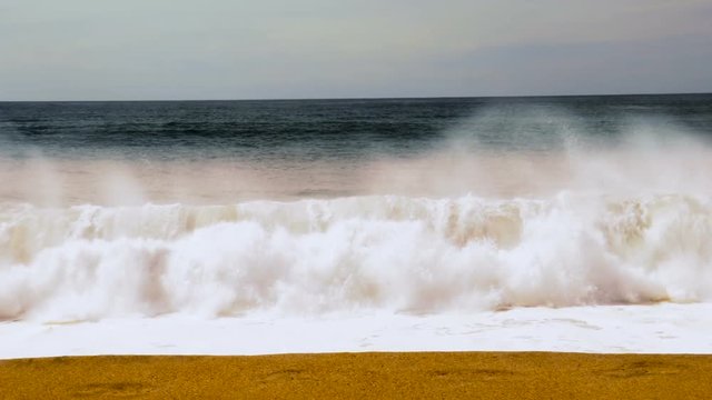 A powerful large wave crashes immediately off shore on to land