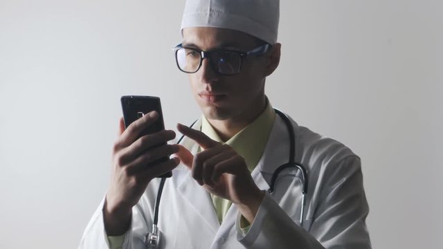 The doctor uses a smartphone. Medical worker surfing the Internet using a mobile phone.