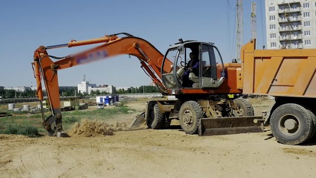 Orange excavator in slow motion. Construction of a residential multi-apartment complex in the city. Construction. Stock video footage.