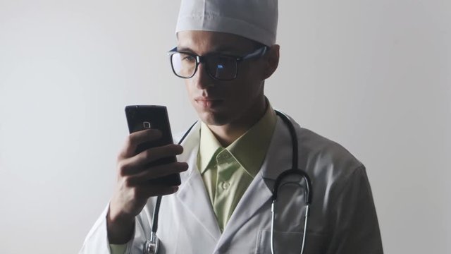 The doctor uses a smartphone. Medical worker surfing the Internet using a mobile phone.